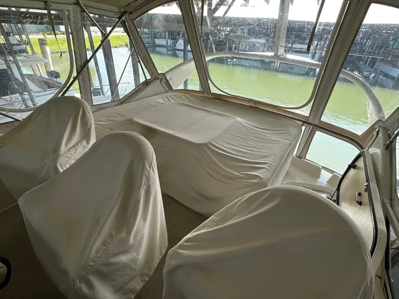 Slide: The Image of 1999 Sea Ray 400 Sedanbridge interior with covered seating and large windows overlooking water. - 29