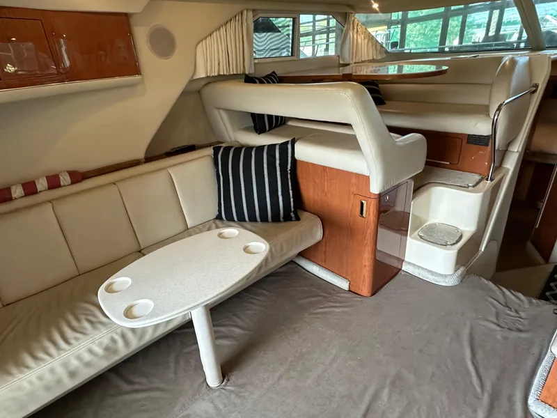 Slide: The Image of Interior of 1999 Sea Ray 400 Sedanbridge with beige seating and a small table. - 7