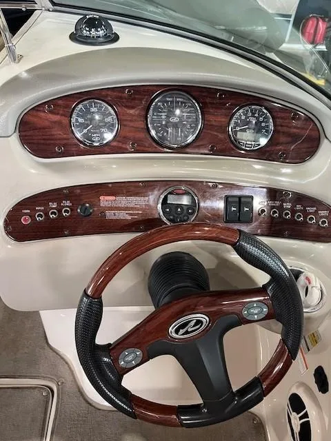 Slide: The Image of 2006 Sea Ray Sundeck 240 dashboard with wood accents and steering wheel. - 17