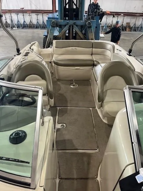 Slide: The Image of 2006 Sea Ray Sundeck 240 interior with beige seating and carpeted floor in a warehouse setting. - 24