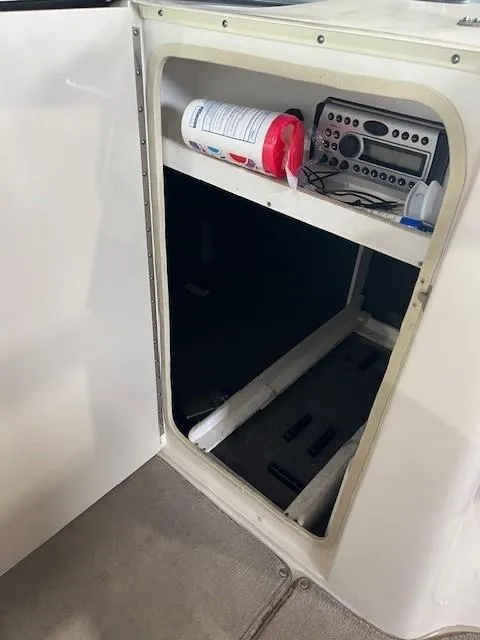 Slide: The Image of 2006 Sea Ray Sundeck 240 storage compartment with stereo system and cleaning supplies. - 25