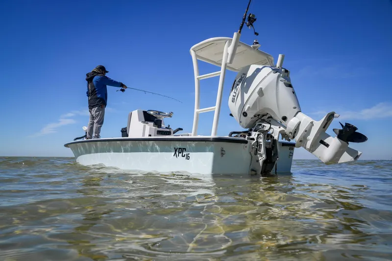 Slide: The Image of Fishing on a Custom XPC 16 boat, 2025 model, in shallow waters under a clear blue sky. - 14