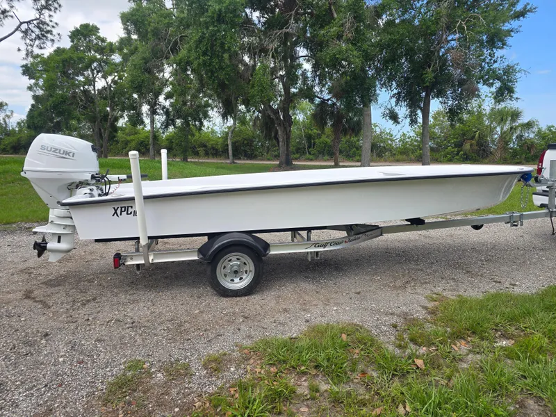 Slide: The Image of Custom XPC 16 boat on trailer, 2025 model, with Suzuki outboard motor, parked outdoors. - 2