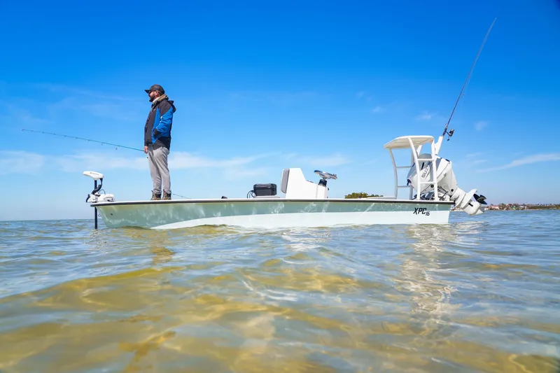 Slide: The Image of Man fishing on Custom XPC 16 boat, 2025 model, in calm waters under clear blue sky. - 8