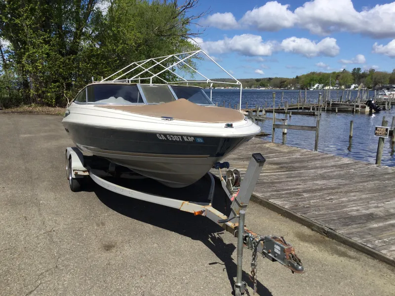 Slide: The Image of 1997 Maxum 2100 SR boat on trailer by lakeside dock under blue sky. - 3