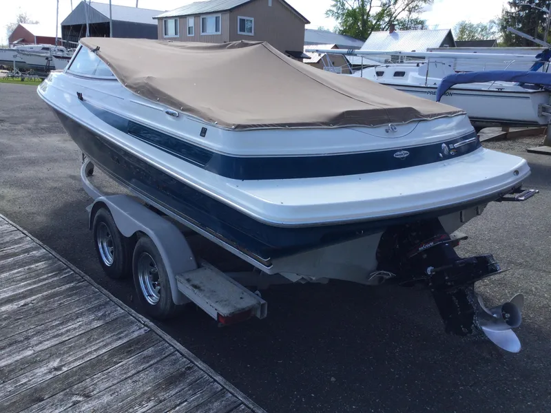 Slide: The Image of 1997 Maxum 2100 SR boat on trailer with beige cover, parked near docks. - 4