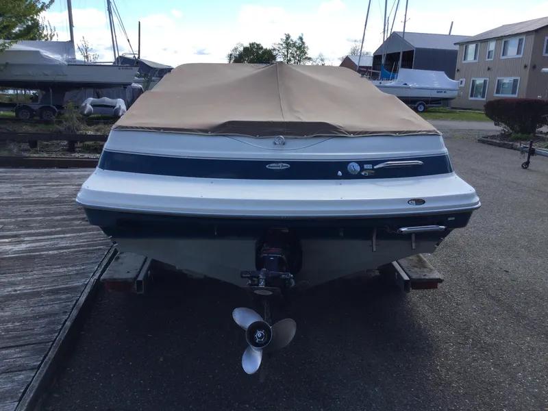 Slide: The Image of 1997 Maxum 2100 SR boat with cover, parked on a trailer in a marina. - 5