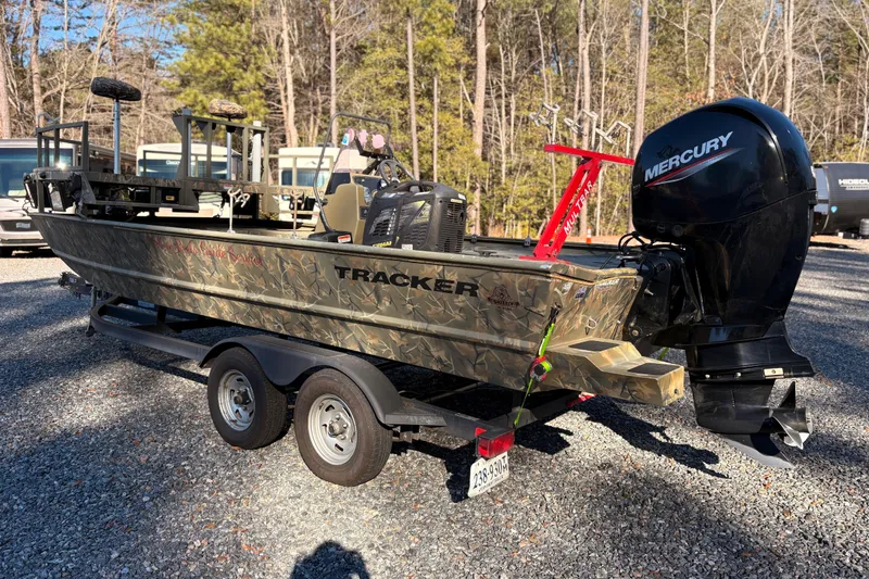 Slide: The Image of 2020 Tracker Grizzly 2072 boat with Mercury engine on a trailer in a wooded area. - 13