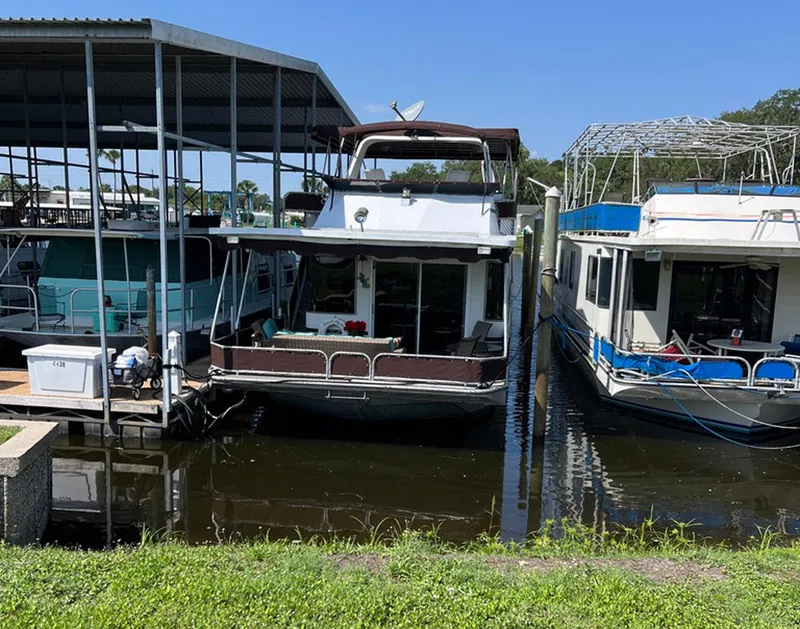 Slide: The Image of Houseboats docked at marina, featuring a 2000 Stardust Cruisers 6816 under a clear blue sky. - 15