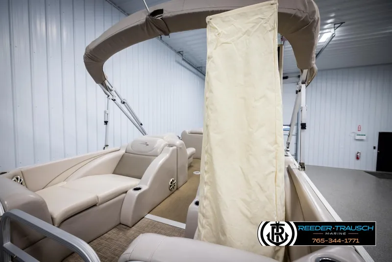 Slide: The Image of 2013 Bennington 2375 GCW pontoon boat interior with beige seating and canopy in showroom. - 25