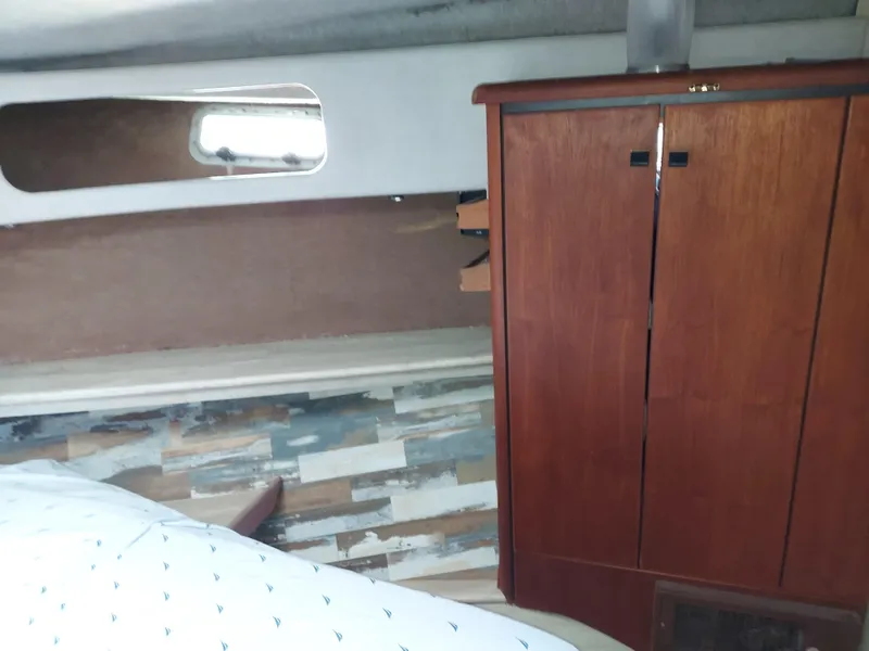 Slide: The Image of 1987 Bayliner 3870 Motoryacht interior with wooden cabinet and bed, showcasing cozy cabin design. - 13