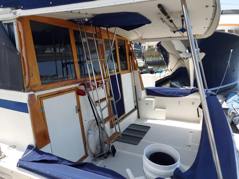 Slide: The Image of 1987 Bayliner 3870 Motoryacht deck with wooden accents and blue seating. - 2
