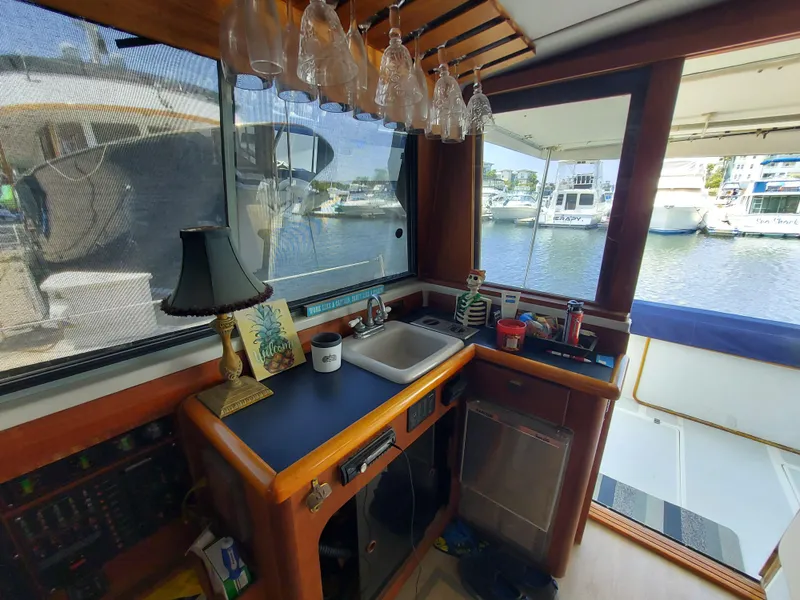 Slide: The Image of Interior of 1987 Bayliner 3870 Motoryacht with kitchenette, glassware, and marina view. - 5