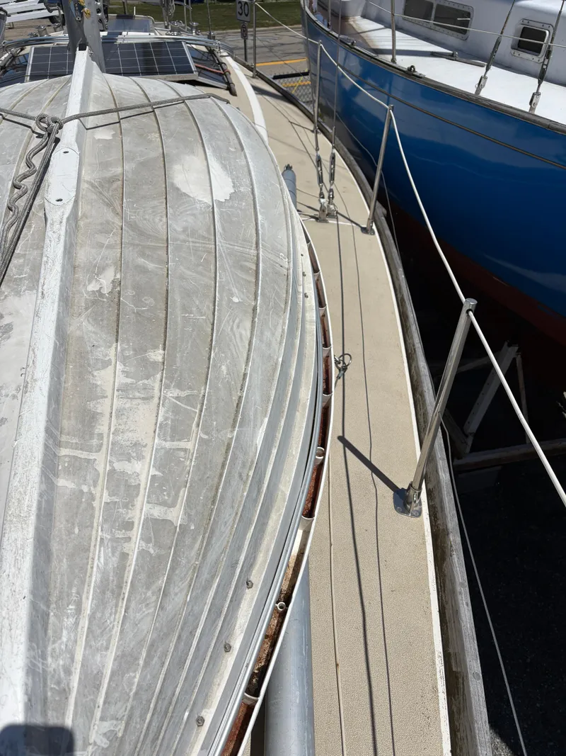 Slide: The Image of 1972 Tartan 34C sailboat deck view, showing weathered surface and adjacent blue boat. - 11