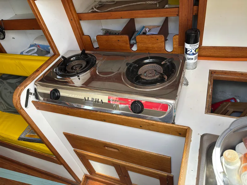 Slide: The Image of Vintage Tartan 34C yacht kitchen with dual-burner stove, wooden cabinetry, and yellow seating, 1972 model. - 31