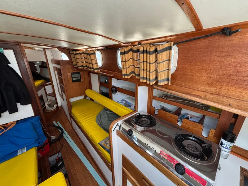 Slide: The Image of 1972 Tartan 34C yacht interior with yellow seating, wooden cabinetry, and a compact stove. - 32