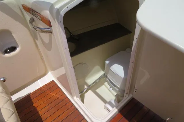 Slide: The Image of 2021 Chris-Craft Launch 27 boat interior with compact toilet and wooden flooring. - 26