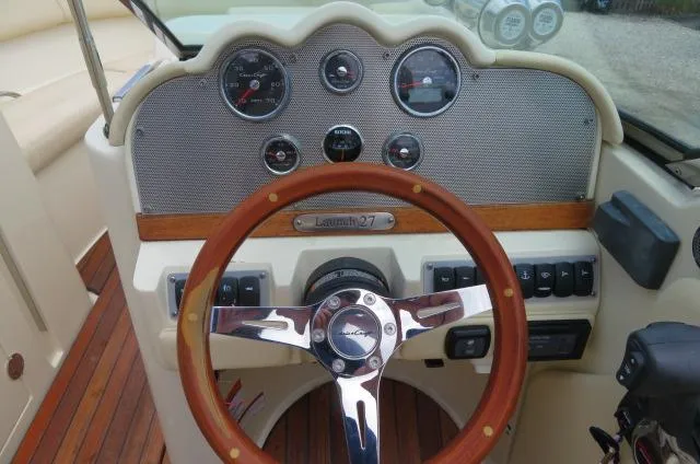 Slide: The Image of 2021 Chris-Craft Launch 27 dashboard with wooden steering wheel and classic gauges. - 28