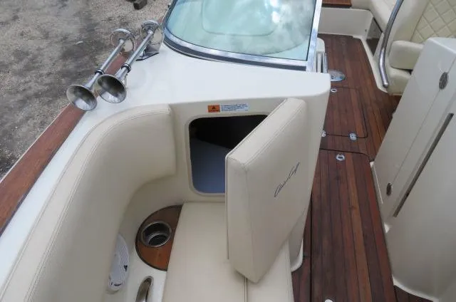 Slide: The Image of 2021 Chris-Craft Launch 27 interior with open storage, beige seating, and wood flooring. - 34