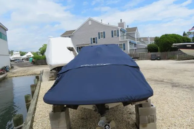 Slide: The Image of 2021 Chris-Craft Launch 27 boat covered, parked on a gravel lot near waterfront homes. - 4