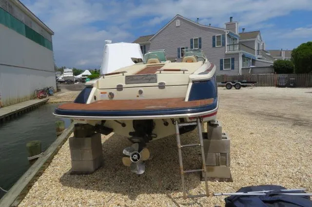 Slide: The Image of 2021 Chris-Craft Launch 27 boat on blocks, dockside, with houses in the background. - 5