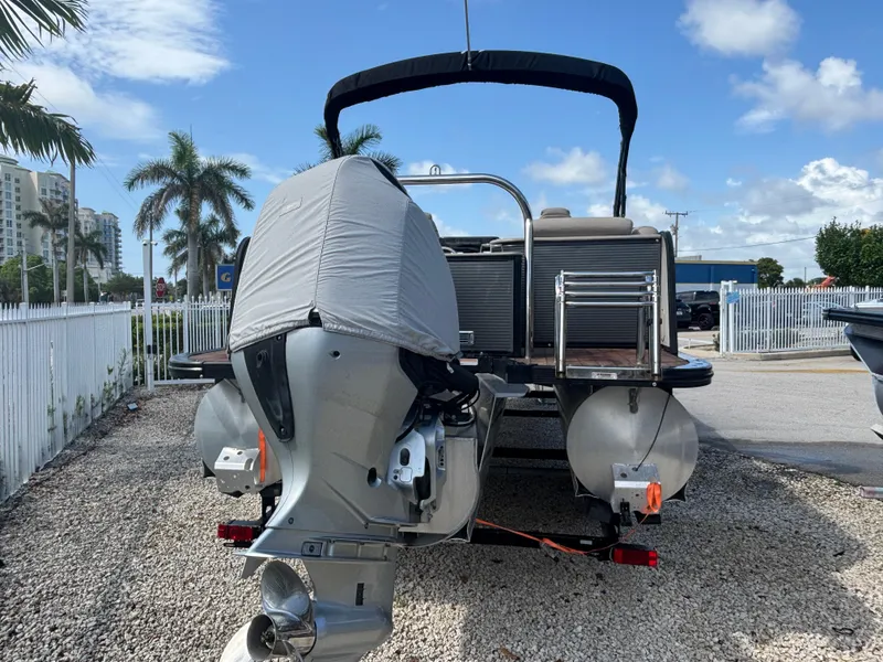 Slide: The Image of 2018 Avalon Catalina Platinum Quad Lounge boat with covered outboard motor, parked on gravel. - 8