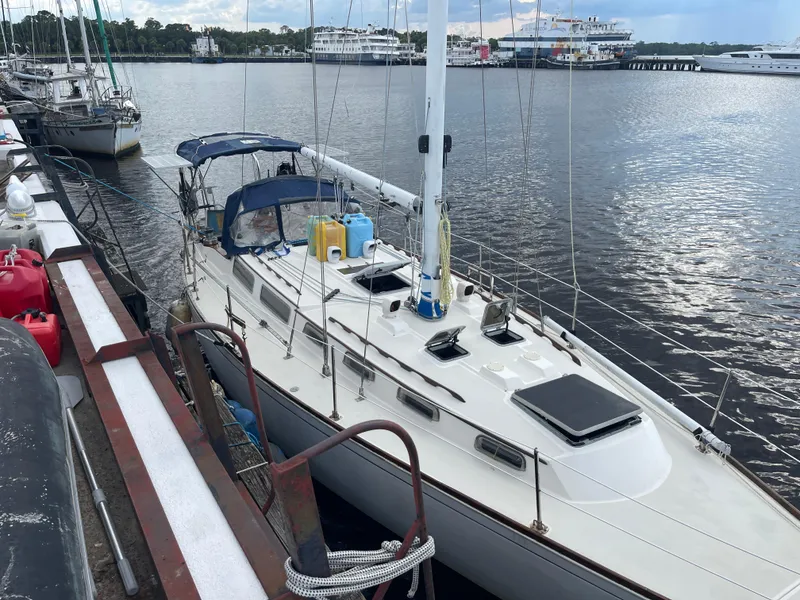 The Image of 1983 Sabre Mk I Swing Keel sailboat docked at a marina, with blue canopy and equipment on deck. - 0