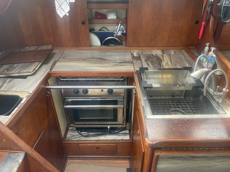 Slide: The Image of 1983 Sabre 38 Mk I Swing Keel yacht kitchen with stove, sink, and wooden cabinetry. - 12