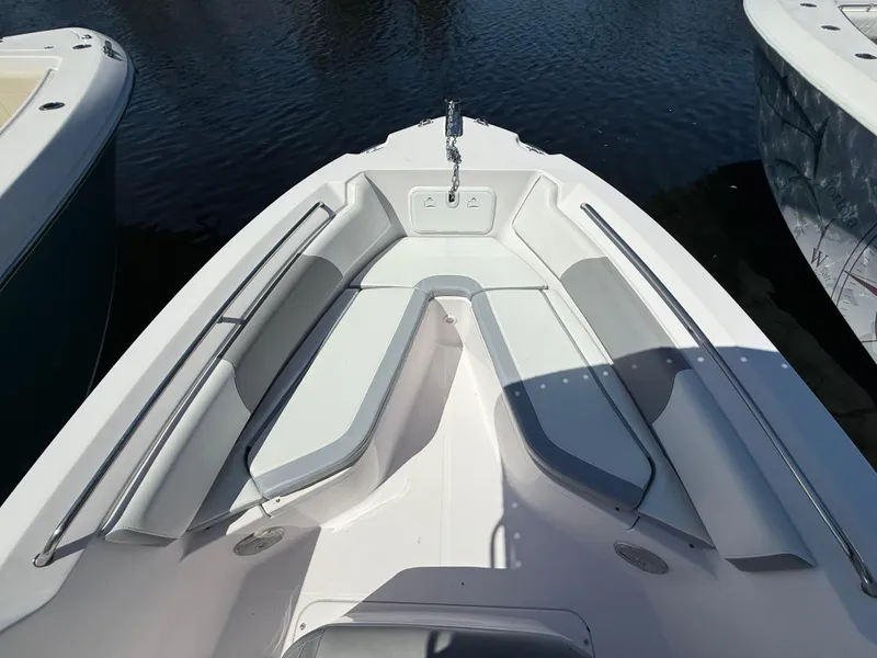 Slide: The Image of 2019 Pro-Line 23 Sport boat bow with cushioned seating and anchor, docked on water. - 13