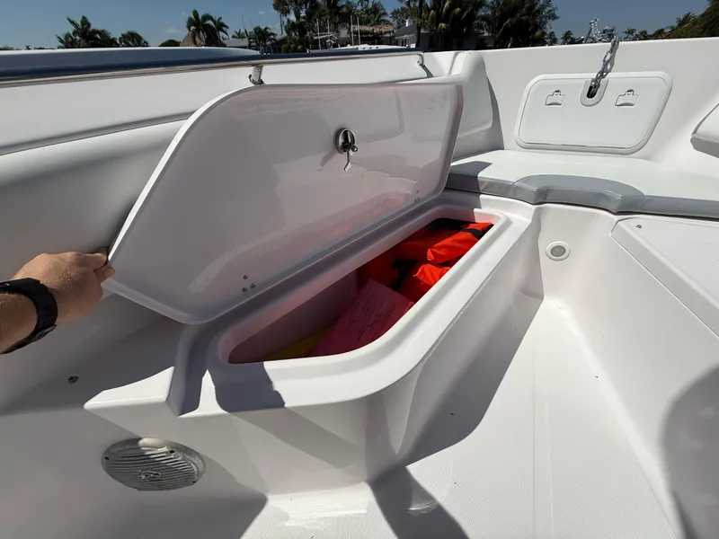 Slide: The Image of 2019 Pro-Line 23 Sport boat storage compartment with open hatch, revealing safety equipment. - 14
