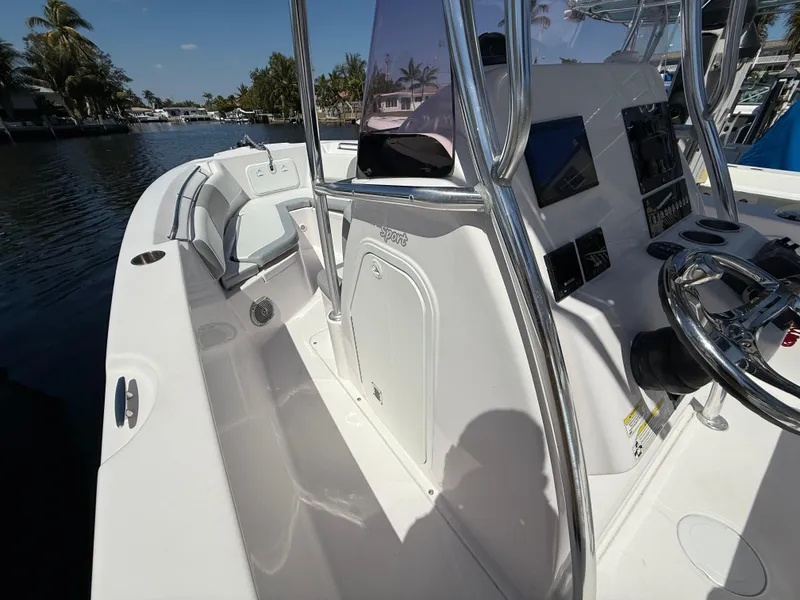 Slide: The Image of 2019 Pro-Line 23 Sport boat interior with steering console and seating, docked by a canal. - 18