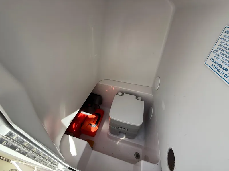 Slide: The Image of 2019 Pro-Line 23 Sport boat interior with compact toilet and storage area. - 19