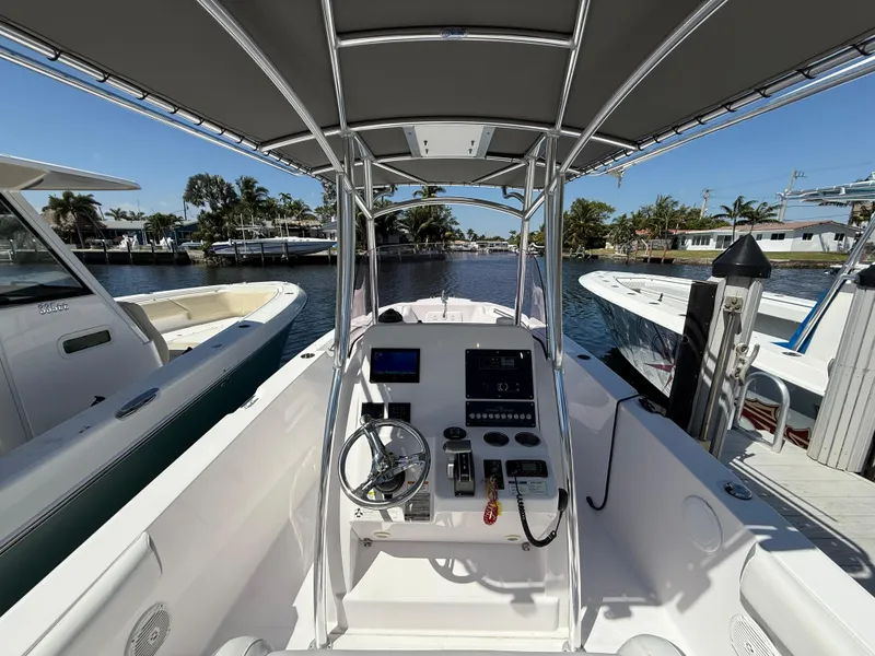 Slide: The Image of 2019 Pro-Line 23 Sport boat interior with steering console, docked by waterfront homes. - 21
