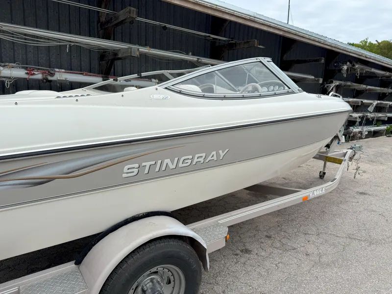 The Image of 2003 Stingray 200LX boat on trailer, parked outdoors near storage facility. - 0