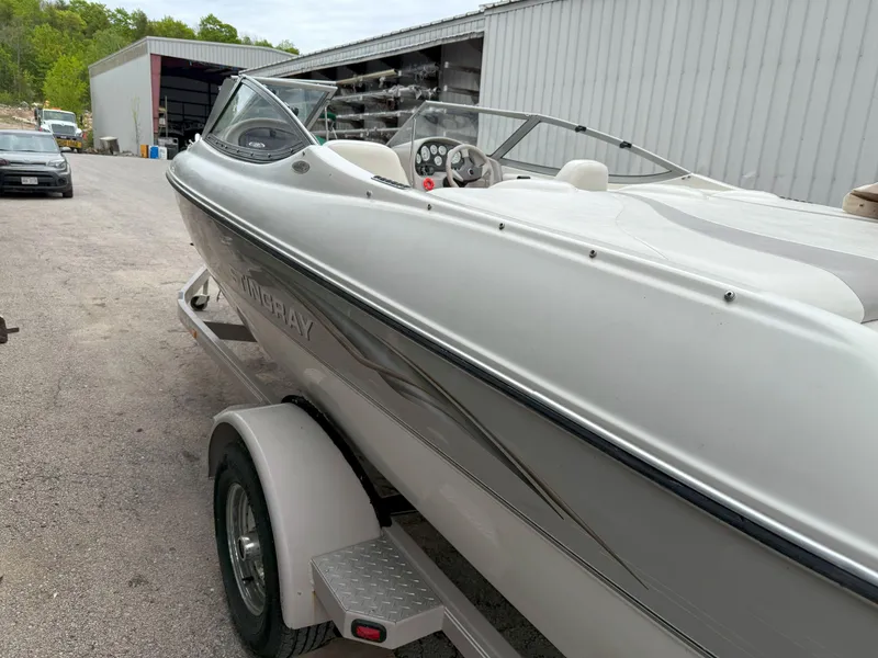 Slide: The Image of 2003 Stingray 200LX boat on trailer near a warehouse. - 2