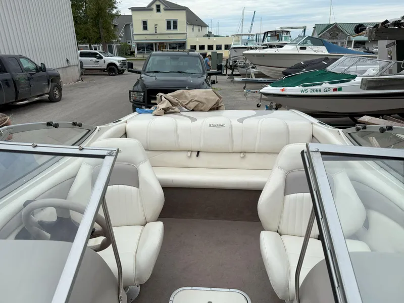Slide: The Image of 2003 Stingray 200LX boat with white interior, parked near other boats and vehicles. - 23