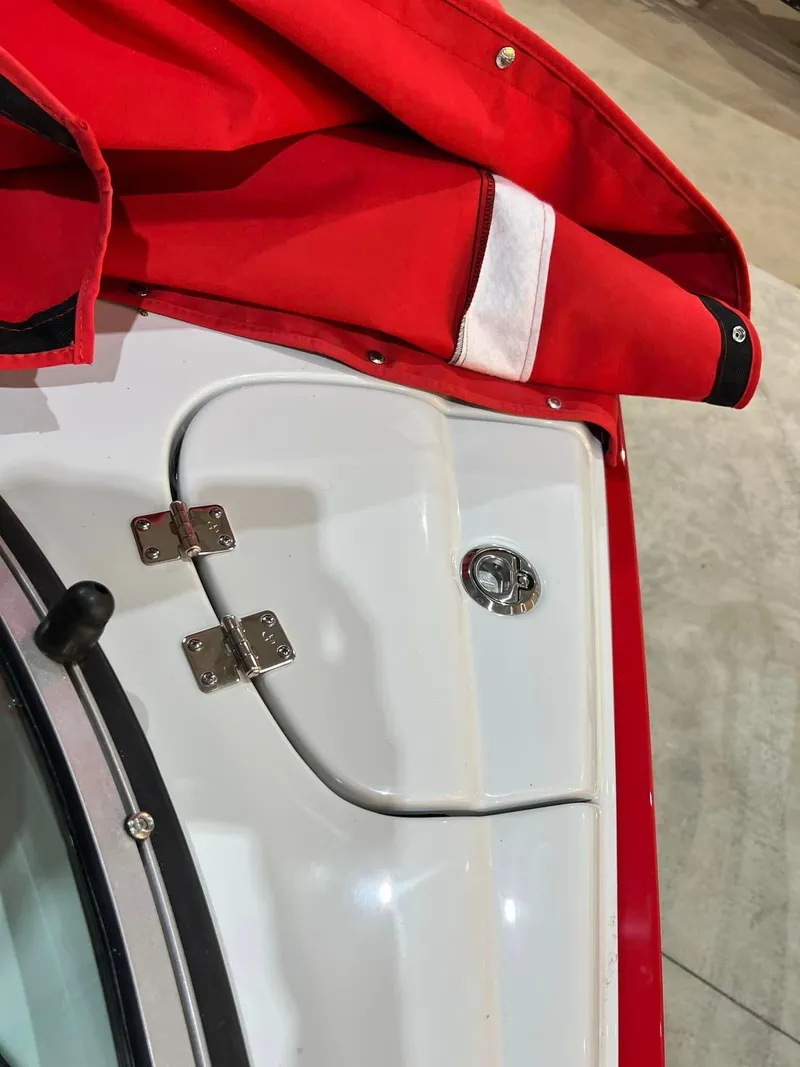 Slide: The Image of 2024 Crownline 250XSS boat with red cover and stainless steel hinges. - 2