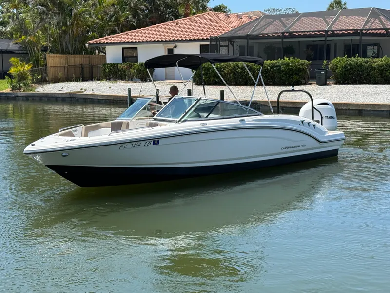 Slide: The Image of 2021 Chaparral 23 SSi OB boat on a calm waterway near a house. - 3