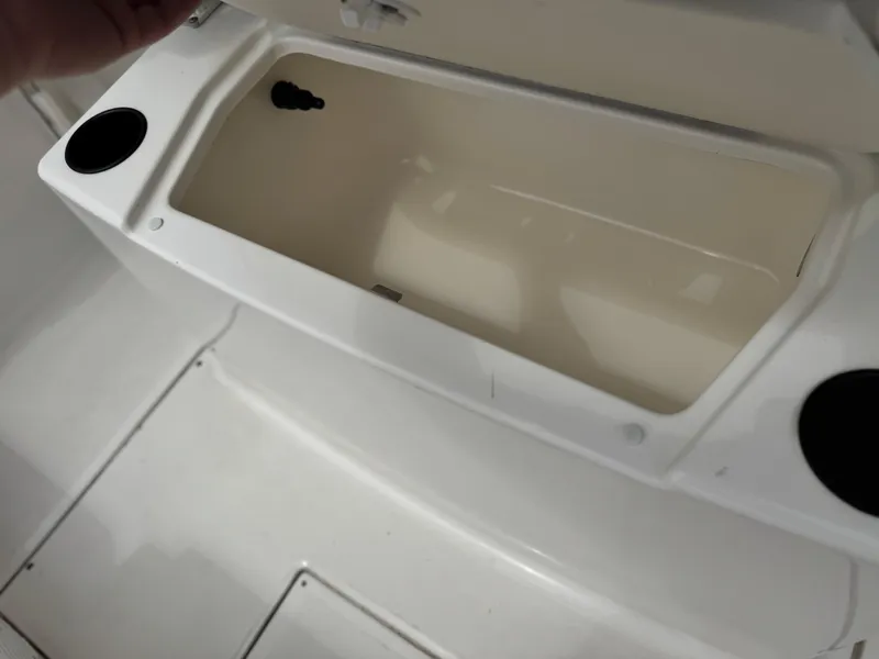 Slide: The Image of 2022 Bayliner Trophy T22CC storage compartment with open lid and cup holders. - 23