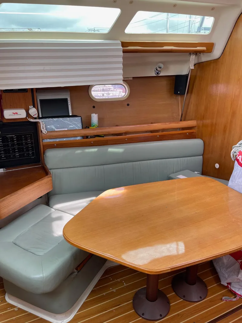 Slide: The Image of 2004 Catalina 350 yacht interior with wooden table, cushioned seating, and natural light. - 11