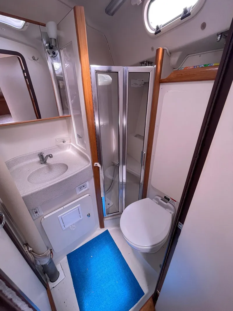 Slide: The Image of 2004 Catalina 350 yacht bathroom with shower, sink, and toilet, featuring a blue mat. - 15