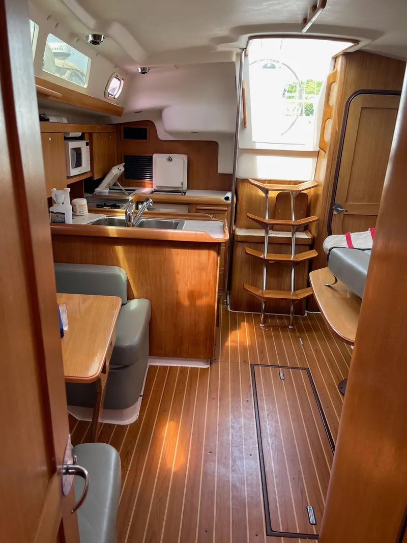 Slide: The Image of Interior of 2004 Catalina 350 sailboat with wood finish, kitchenette, and seating area. - 16