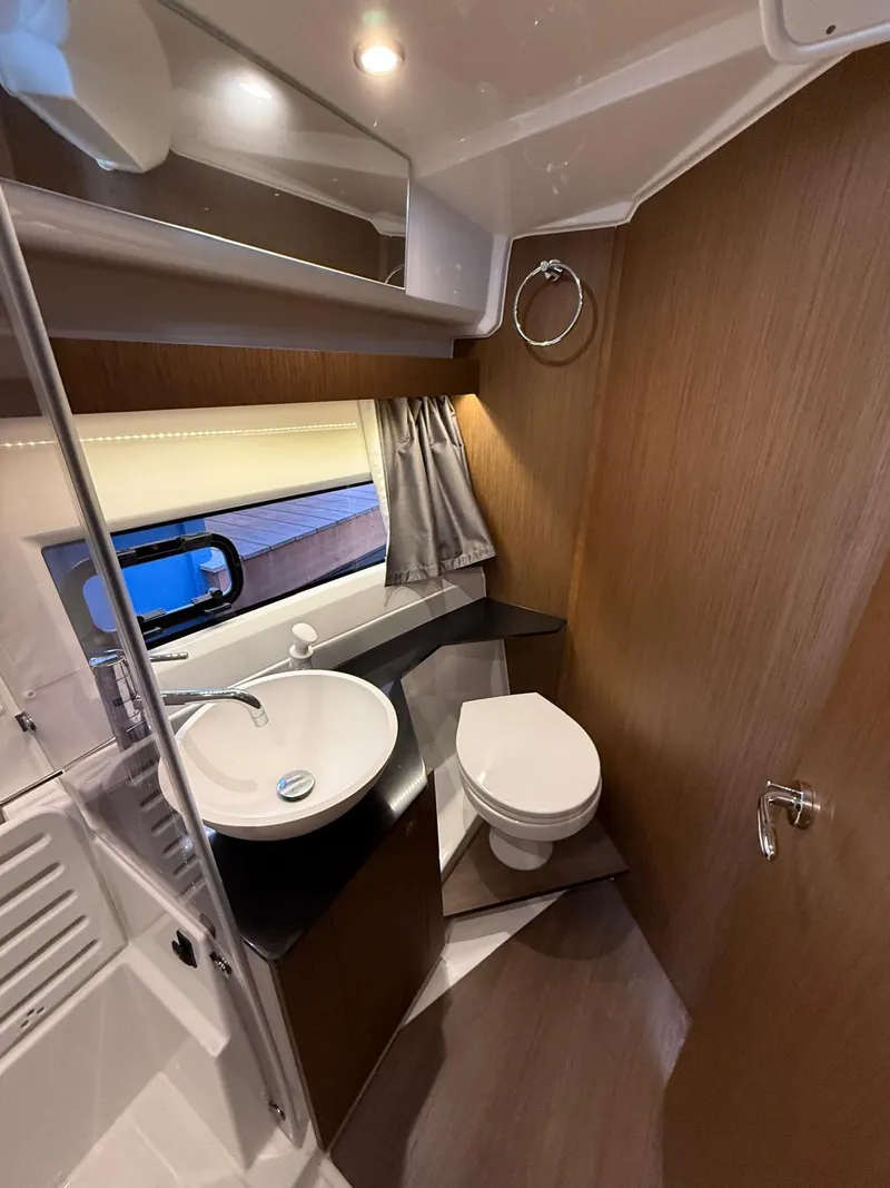 Slide: The Image of 2021 Jeanneau NC Weekender 1095 bathroom with modern fixtures and wood accents. - 12