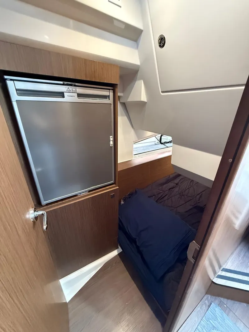 Slide: The Image of 2021 Jeanneau NC Weekender 1095 cabin interior with compact fridge and cozy sleeping area. - 13