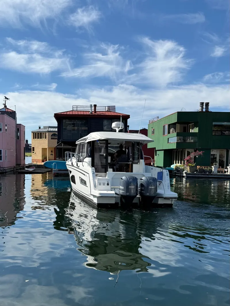 Slide: The Image of 2021 Jeanneau NC Weekender 1095 boat docked near colorful waterfront buildings. - 2