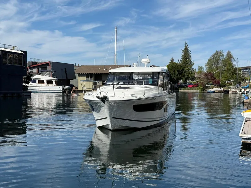 Slide: The Image of 2021 Jeanneau NC Weekender 1095 boat on calm water, surrounded by marina and trees. - 23