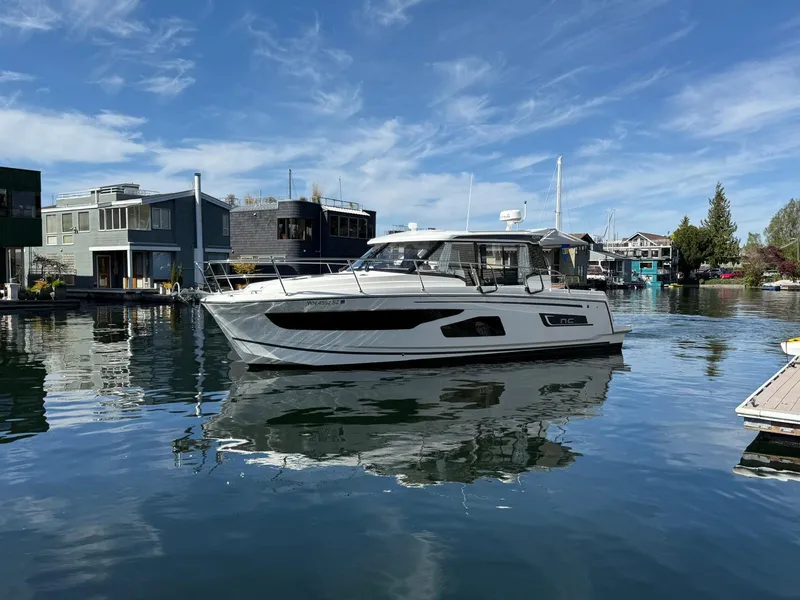 Slide: The Image of 2021 Jeanneau NC Weekender 1095 boat docked on calm water under a clear blue sky. - 3