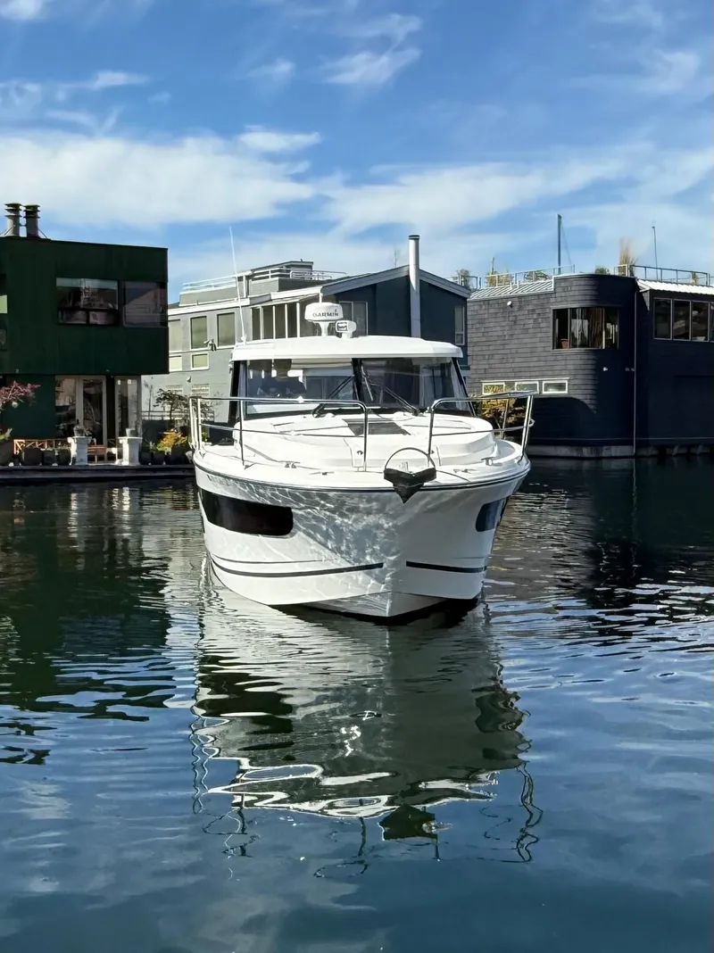 Slide: The Image of 2021 Jeanneau NC Weekender 1095 boat docked on calm water, surrounded by modern houseboats. - 5