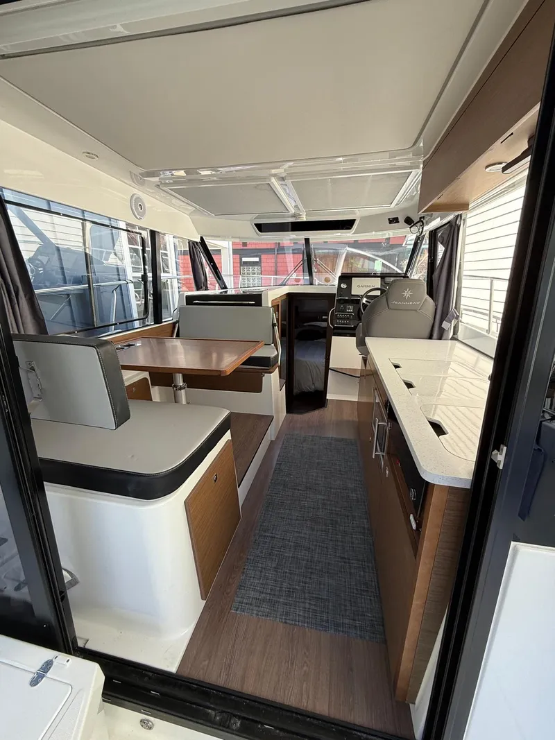 Slide: The Image of 2021 Jeanneau NC Weekender 1095 interior with modern seating, dining area, and helm station. - 8