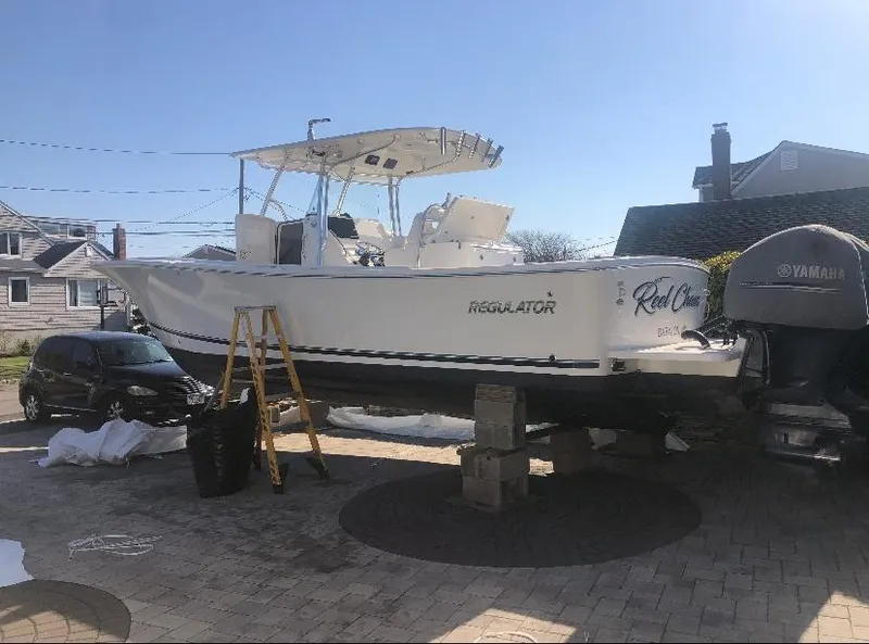 Slide: The Image of 2019 Regulator 31 FS boat on blocks, parked outdoors with ladder and Yamaha engine. - 10